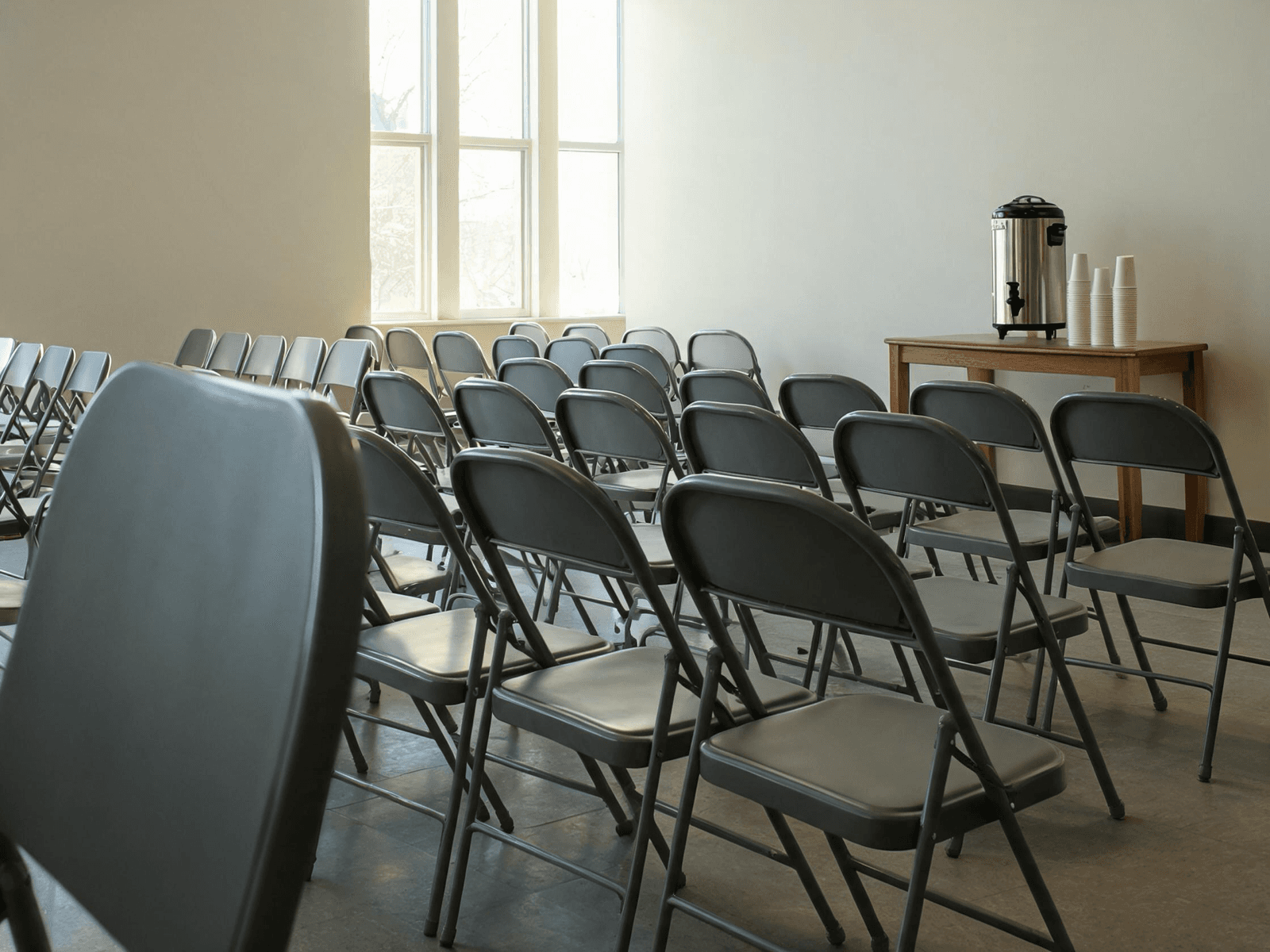 Community meeting room with folding chairs and a coffee urn, set and waiting